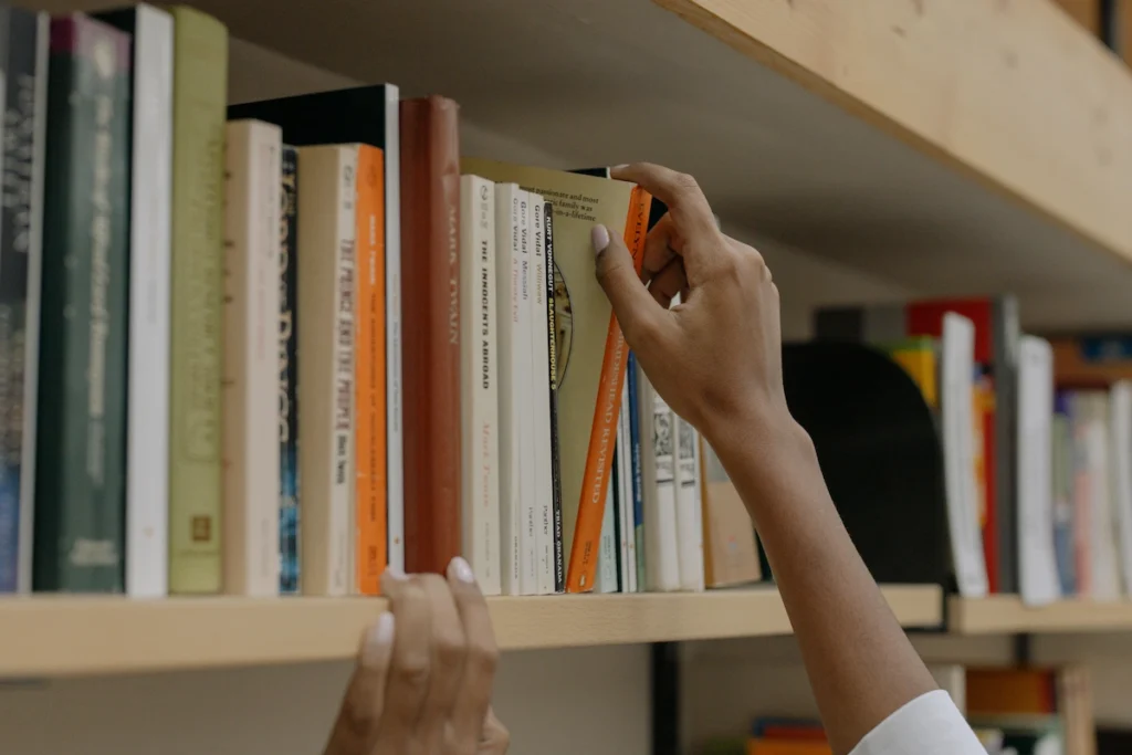 Student choosing a book from the library shelf.