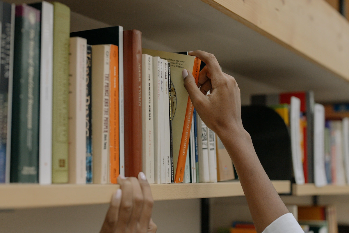 Student choosing a book from the library shelf.