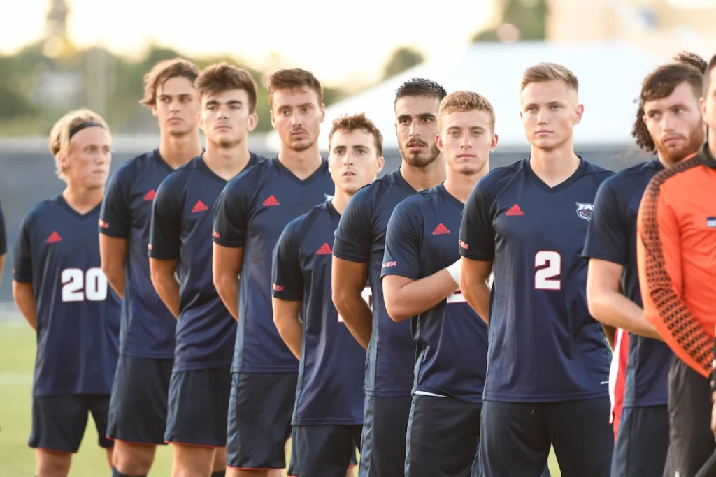College soccer team line up for the national anthem
